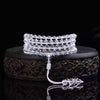 Coiled clear glass mala bracelet on a dark carved stand