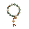 Green gradient bodhi seed bracelet with a gold-tone charm and tassel on a white background