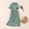 A green short sleeve midi dress with a polo collar laid flat next to a straw bag.