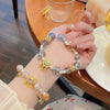 Close up of a handmade glass bead bracelet with a gold peace lock charm on a wrist
