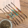 A collection of Tibetan style handwoven beaded bracelets with bell charms on a wooden surface.
