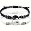 Two woven cord bracelets with Yin Yang charms, one black and one white
