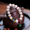 White bodhi seed bracelet with pumpkin shaped beads and a lotus charm resting on a teapot