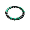 Close up of a green and black beaded glass bracelet on a wooden surface