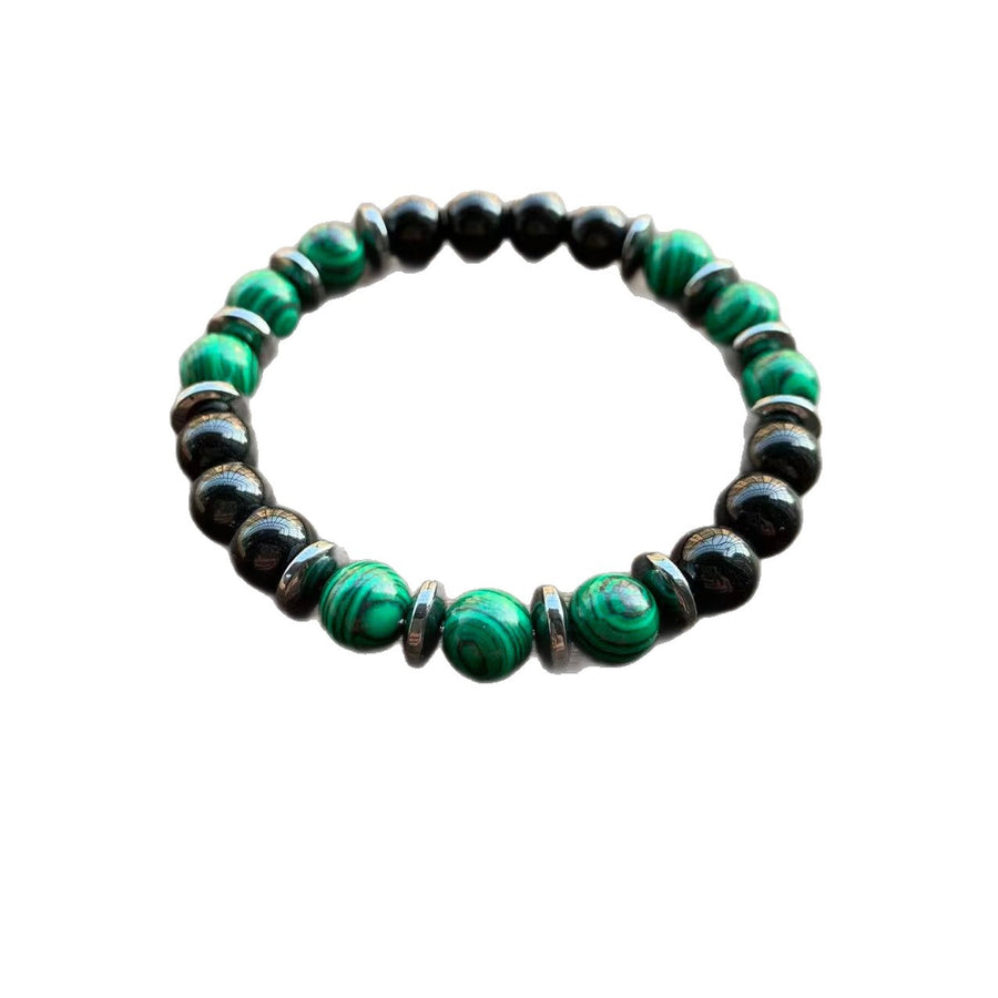Close up of a green and black beaded glass bracelet on a wooden surface