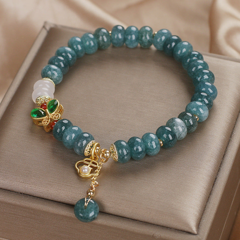 Green crystal abacus bead bracelet with gold butterfly charm on beige box