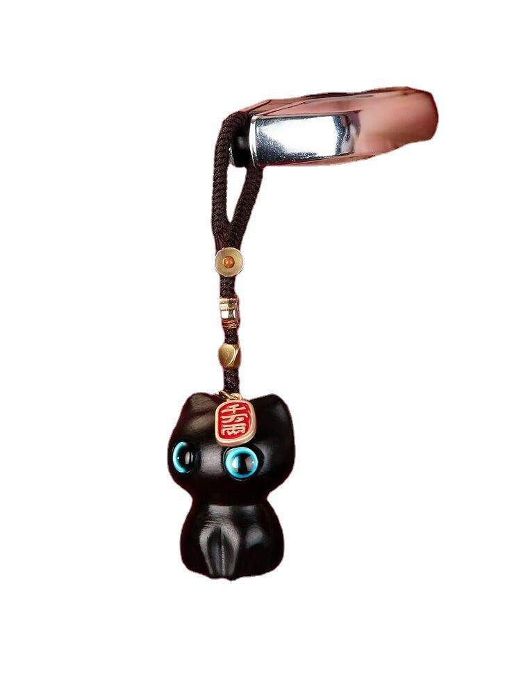Black sandalwood lucky cat keychain with blue eyes hanging on a brown cord