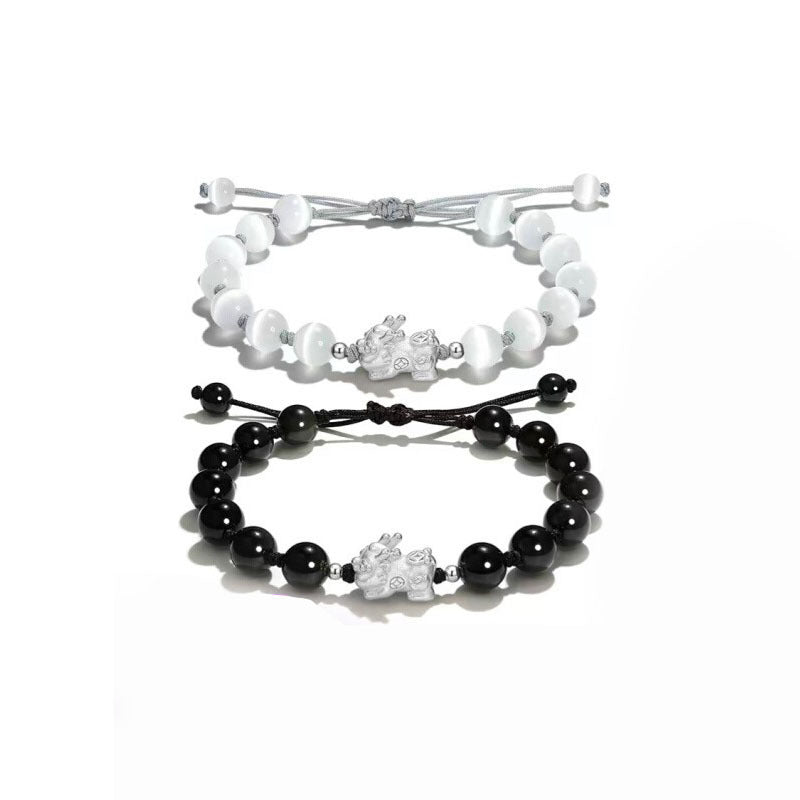 Black and white beaded bracelets with silver Pixiu charms on a white background