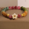 Colorful tourmaline beaded bracelet with a central white flower charm and gold-tone spacers