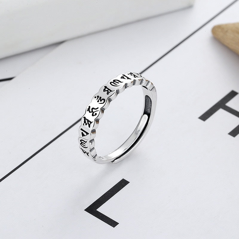 Silver-tone copper ring with Six True Words engraving on a white surface