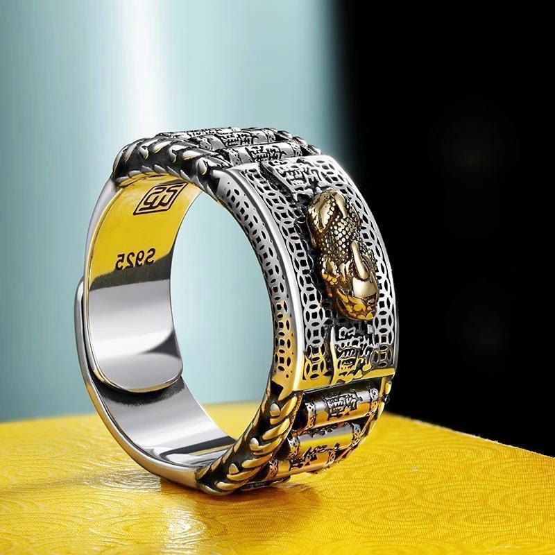 Close up of a silver and gold metal ring with a Pixiu head and prayer wheel details