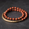 Double wrap Red Jasper bracelet with gold-tone curved bar on dark background