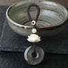 Close up of a black obsidian peace buckle keychain with a white lotus bead
