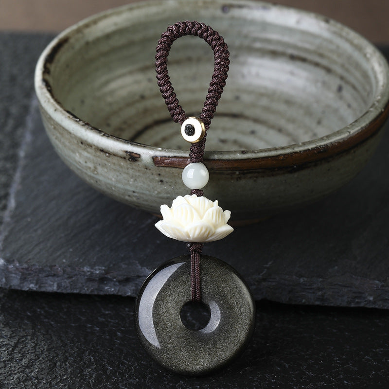Close up of a black obsidian peace buckle keychain with a white lotus bead