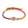 Close-up of a multicolor braided cord bracelet with a central heart knot on a red background