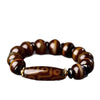 Hand holding a brown agate bracelet with a long central Dzi bead
