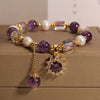 Close up of purple amethyst beaded bracelet with gold flower charm