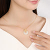 Woman wearing a white jade pendant necklace with a gold flower accent