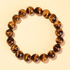 Close-up of a polished yellow tiger eye bead bracelet on a neutral background