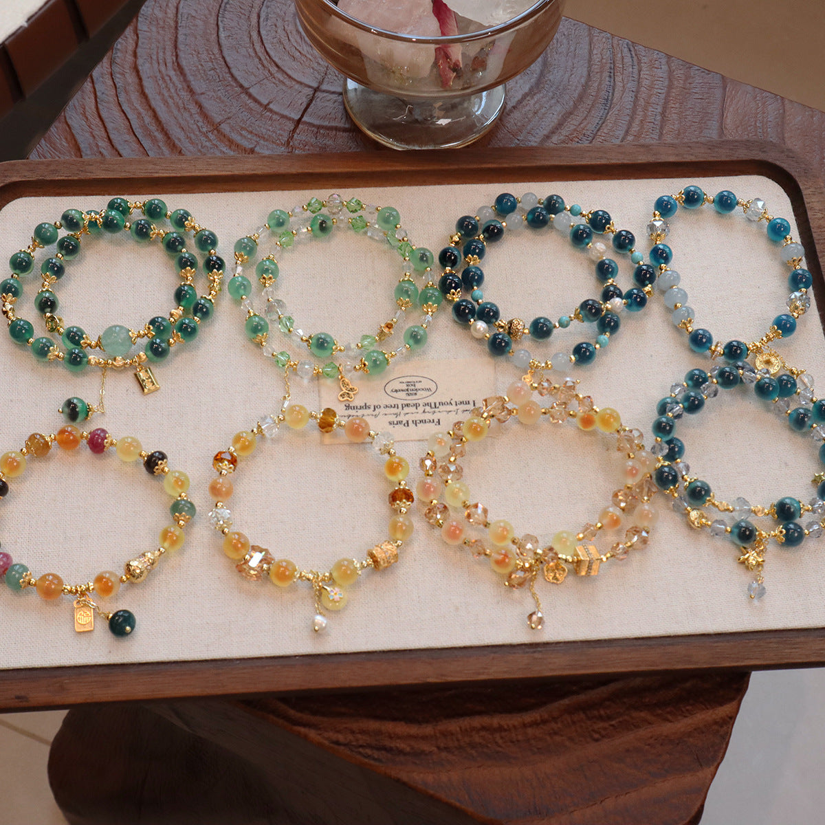 Tray displaying various colorful natural candy agate beaded bracelets with gold charms
