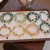 Tray displaying various colorful natural candy agate beaded bracelets with gold charms