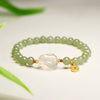 Light green beaded bracelet with a central white rabbit carving and a small gold coin charm