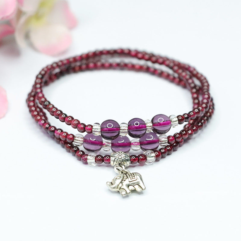 Triple wrap garnet bracelet with silver-tone elephant charm on white background