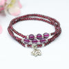 Triple wrap garnet bracelet with silver-tone elephant charm on white background