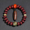 Red bodhi seed bracelet with a wooden lion charm resting on a wood block