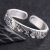 Close up of a silver open cuff bracelet with a carved dragon design and gold highlights
