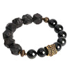 Close-up of a black obsidian bracelet with textured stones and a gold-tone honeycomb bead