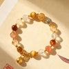 Close-up of a multi-colored crystal beaded bracelet with gold-tone charms on a beige background