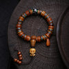 Tibetan style bone bead bracelet with skull charm resting on dark wood
