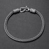 Close-up of a vintage copper braided bracelet with a hook clasp on a dark background