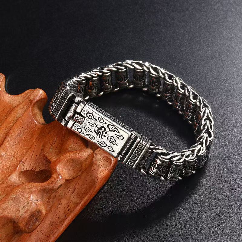 Silver tone copper bracelet with mantra engraving on a dark background