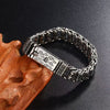 Silver tone copper bracelet with mantra engraving on a dark background
