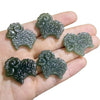 Five dark green carved jade sheep pendants resting on an open palm
