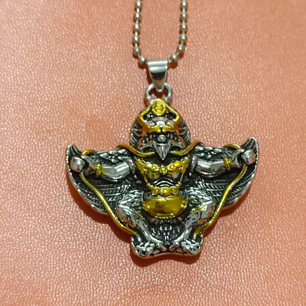Close-up of a gold and silver tone Garuda bird pendant on a silver box chain