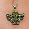 Close-up of a gold and silver tone Garuda bird pendant on a silver box chain