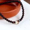 Red sandalwood wood bracelet with a white carved lotus bead on a terracotta dish