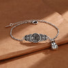 Silver-tone copper bracelet with five coin charms and a money bag pendant on a brown background