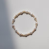 Close up view of a white freshwater pearl bracelet with gold spacer beads on a white background