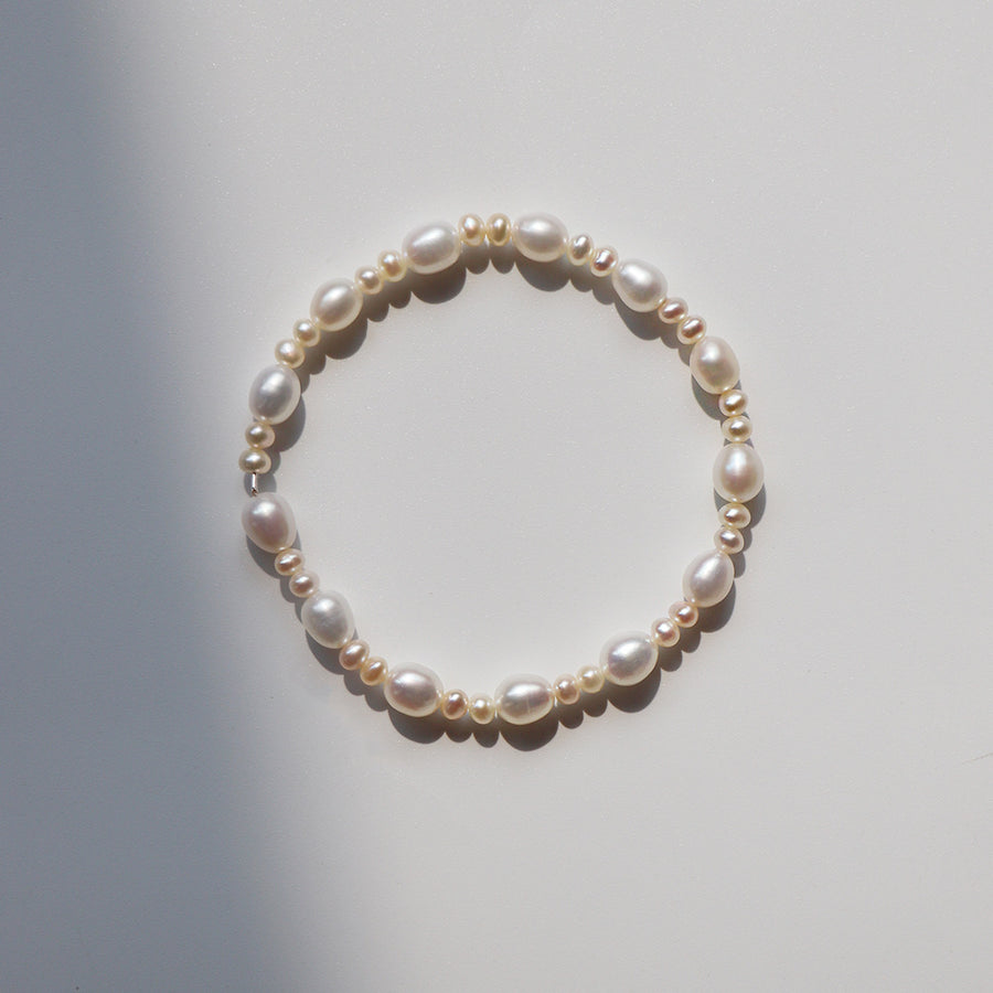 Close up view of a white freshwater pearl bracelet with gold spacer beads on a white background