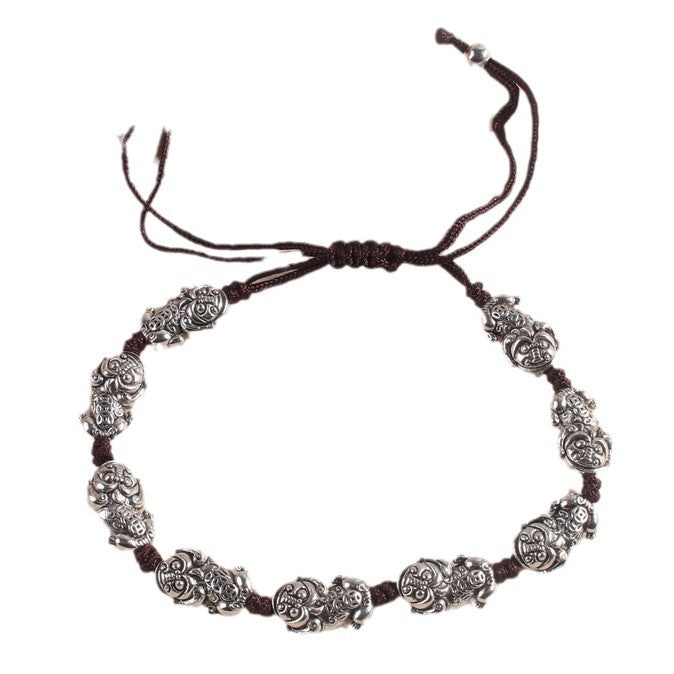 Close up of silver Pixiu beads on a brown woven cord bracelet