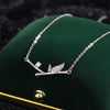 Silver-tone necklace with a horizontal bamboo branch and leaf pendant on a green background
