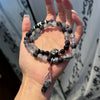 Wrist wearing a double strand bracelet with silver beads, black stones, and a Dzi bead