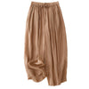 Folded stack of loose cotton linen harem pants in various earth tones