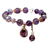 Close up of purple amethyst beaded bracelet with gold teardrop pendant