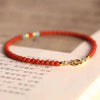 Close-up of a thin red agate beaded bracelet with gold clasp resting on a book page