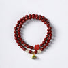 Double wrap cinnabar bracelet with lotus charm on white background